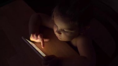 Akşamları telefon kullanan beyaz bir çocuk. Teknolojiye çocuk bağımlılığı. Çocuklar uykusuzluk çekiyor
