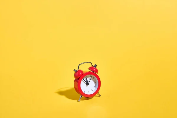 Relógio de alarme retro vermelho no fundo amarelo. Conceito de tempo mínimo. Natal ou véspera de Ano Novo. — Fotografia de Stock