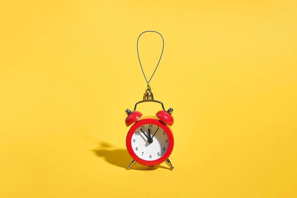 Relógio de alarme retro vermelho no fundo amarelo. Conceito de tempo mínimo. Natal ou véspera de Ano Novo. — Fotografia de Stock