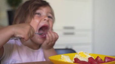Küçük kız evde kahvaltı yapıyor. Aç çocuk. Sağlıklı beslenme. 