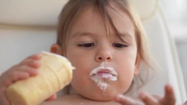 Evde dondurması olan küçük bir kız çocuğu. Lezzetli tatlı yiyecekler. Komik surat.