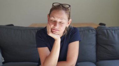 Beyaz, sarışın, 40 'lı yaşlarda, mutlu bir kadın. Evdeki kanepede yalnız başına oturuyor. Mutlu orta yaşlı insanlar