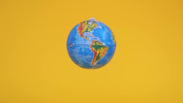Sarı arka planda sıfır yerçekimi küresi uçuyor. Coğrafya sınıfı. Ekoloji konsepti. Dünya günü — Stok video