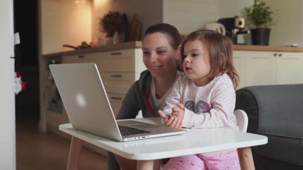 Moeder en kind meisje zitten thuis reclame te kijken naar school video op laptop. Afstandsonderwijs, thuisonderwijs voor kinderen. — Stockvideo