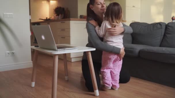 Junge Mutter und Kind umarmen sich zu Hause, während die Mutter von zu Hause aus arbeitet. Glückliche Eltern — Stockvideo