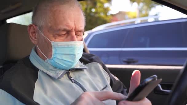 Oudere blanke man zit in de auto en gebruikt de telefoon. actieve moderne pensioengerechtigden — Stockvideo