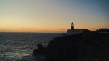 Portekiz 'in Sagres kentindeki Atlantik Okyanusu' nun üzerinde güneş batarken Cape St. Vincent 'taki ikonik deniz fenerinin nefes kesici manzaralarını keşfedin. Bu huzurlu manzarada doğanın güzelliğine tanık olun..