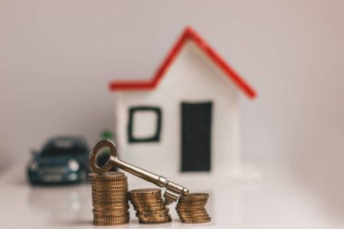 Üstünde tepe-in madeni paralarla bir bulanık ev ve araba arka planda bir yığın anahtar: Emlak, gayrimenkul yatırım, evi ipotek, tasarruf mali kavramı.