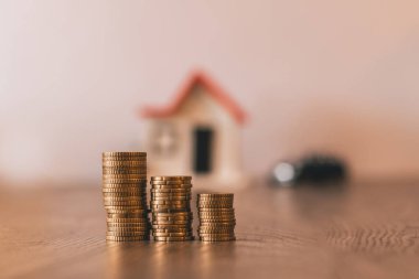 Paralar yığılmış bir bulanık ev ve araba arka planda: Emlak, gayrimenkul yatırım, evi ipotek, tasarruf mali kavramı.