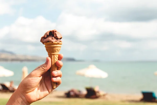 Hand Holding Chocolade Ijs Met Een Strand Achtergrond — Stockfoto