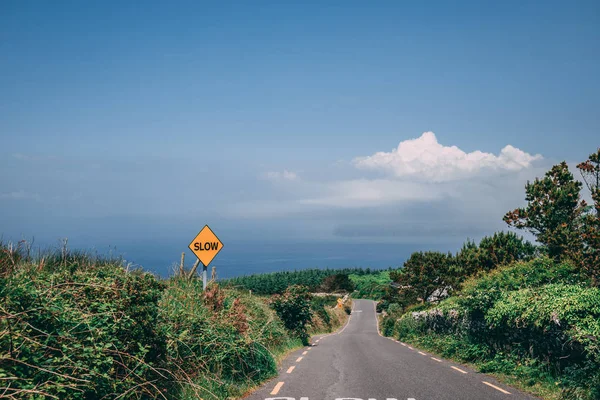 Slow warning sign down a steep rural countryside in county Kerry, Ireland