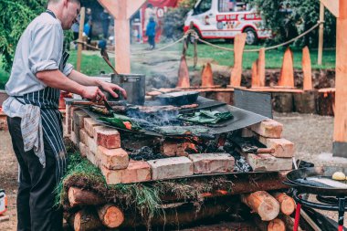 20th Mayıs 2018, Cobh, İrlanda - somon pişirme bir adam yaprakları ve et ile kaplı üzerinde rustik Barbekü