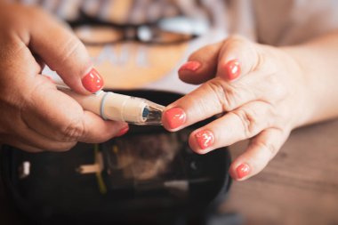 Kadın el lancet şekeri ölçüm cihazı tarafından kan şeker seviyesini kontrol etmek için bir parmağına kullanarak yakın çekim