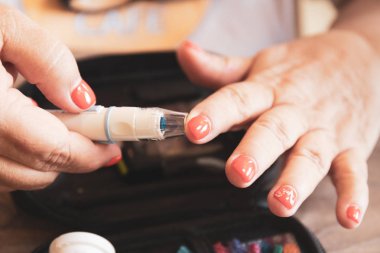 Kadın el lancet şekeri ölçüm cihazı tarafından kan şeker seviyesini kontrol etmek için bir parmağına kullanarak yakın çekim