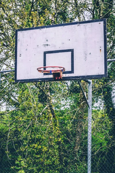 Close up of an abandoned basketball hoop with no net and rusted rim