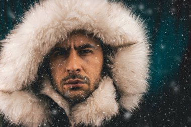 Kameraya bakarak kar ile eskimo bir ceket giymiş beyaz bir adam portresi kapatın