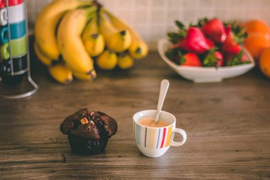 Tam espresso fincan ve arka planda sağlıklı meyve ile ahşap bir masa üstünde çikolata kek