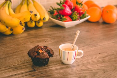 Tam espresso fincan ve arka planda sağlıklı meyve ile ahşap bir masa üstünde çikolata kek