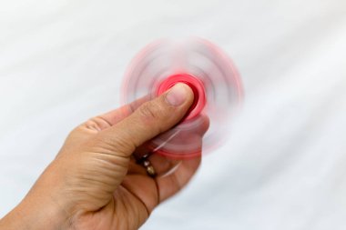 Bir kırmızı topluca spinner beyaz bir arka planda tutan el