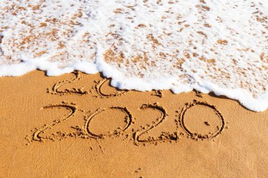 2020 yılı kuma çizilmiş sahilde bir dalga tarafından yıkanmış olan