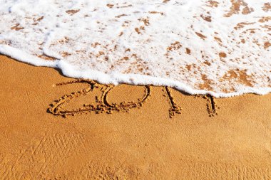 2019 yılı kuma çizilmiş sahilde bir dalga tarafından yıkanMış