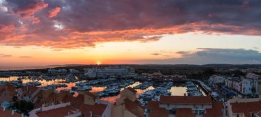 21 Nisan 2019, Vilamoura, Portekiz - dramatik bulutlu bir günde uzakta gün batımı olarak marina havadan panoramik görünümü.