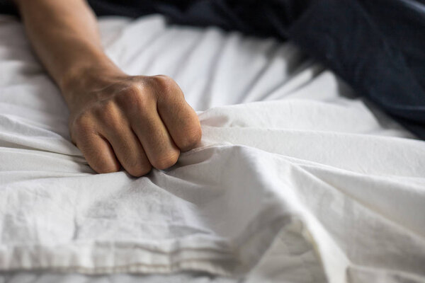 Крупная деталь женской руки, хватающейся за простыни
