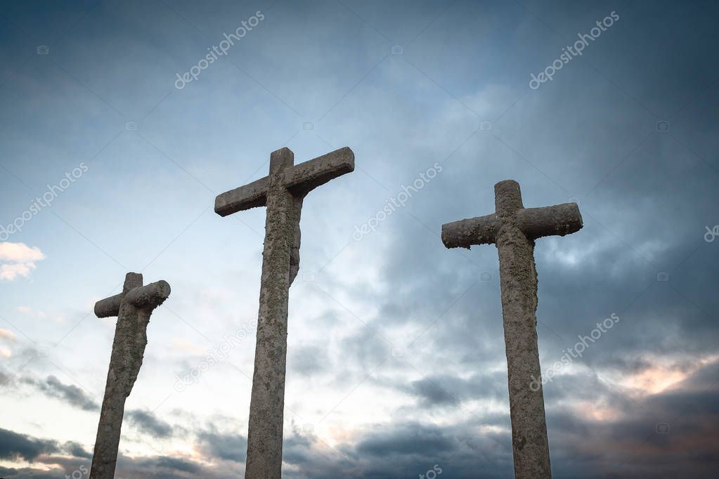 Silhouette of three religious crosses carved in stone with sky at dus