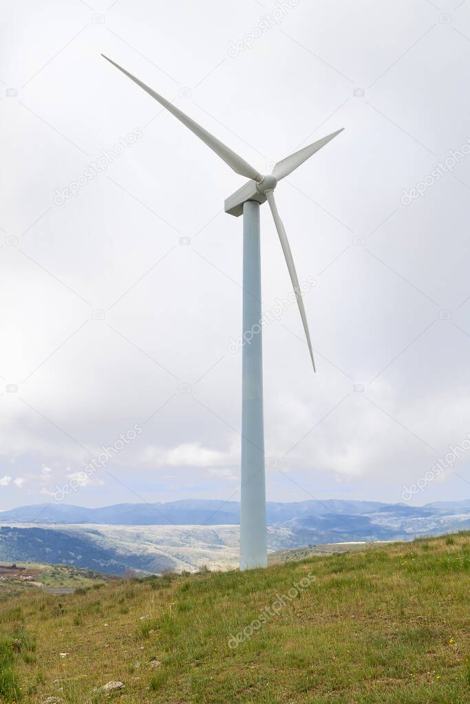 eolic wind mill in the foreground with background in complementary blue and green colour