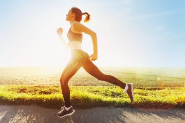 Güzel genç kız günbatımında koşu. Yaşam tarzı spor fotoğraf