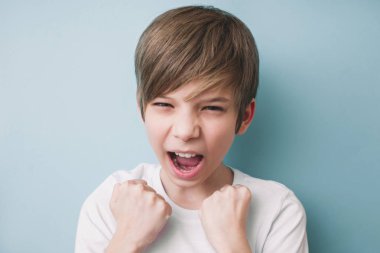 Boy screams and demonstrates his fists in victorious gesture. Emotion Success Concept. Emotion Success Concept clipart