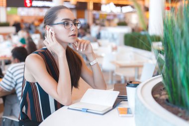 Genç çekici kız bardaklarda bluetooth kulaklık kafede kullanılır. Yaşam tarzı iş portre