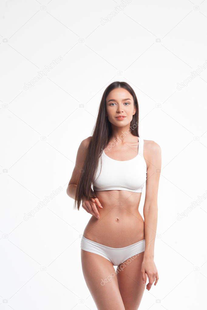 Slim young woman in underwear on white background. Skin and body care concept
