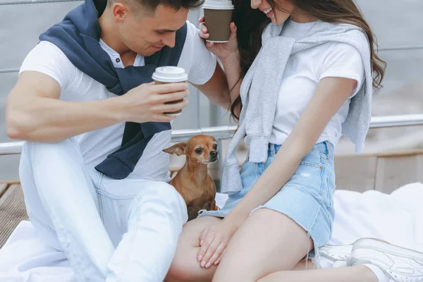 Dog sits on lap of loving couple on sea promenade. Lifestyle Concept