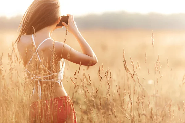 Gün batımında alanındaki kamera ile genç çekici kız. Açık havada romantik kavramı
