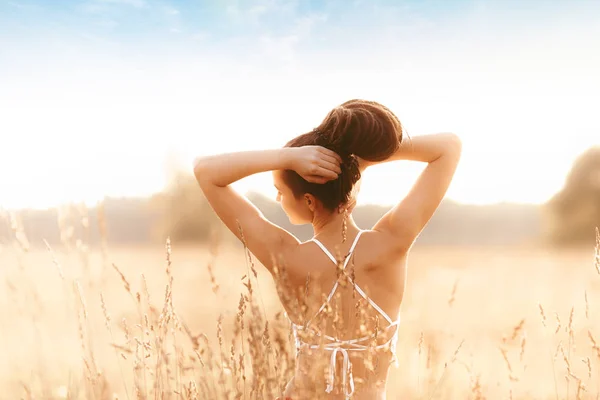 Young attractive girl in field at sunset. Outdoors romantic concept