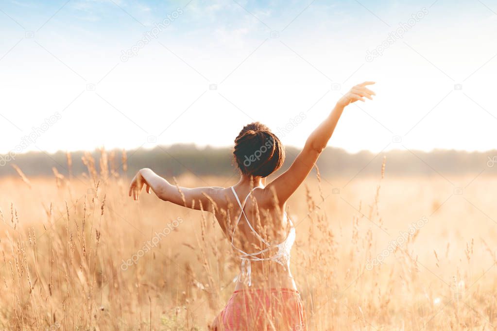 Young attractive girl dancing in field at sunset. Outdoors romantic concept