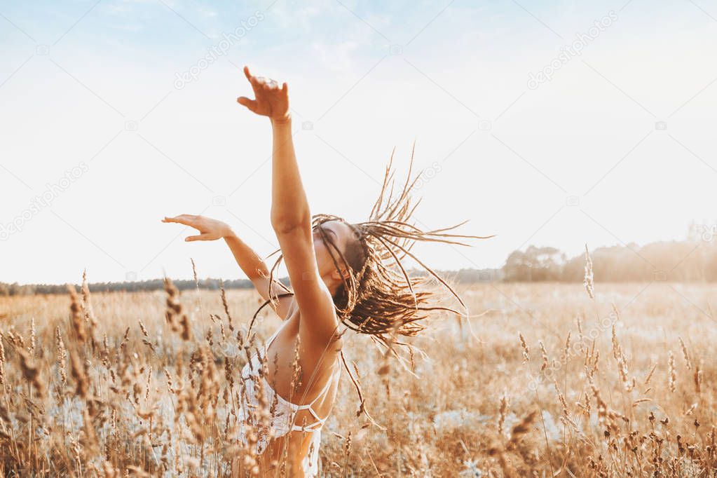 Young attractive girl dancing in field at sunset. Outdoors romantic concept