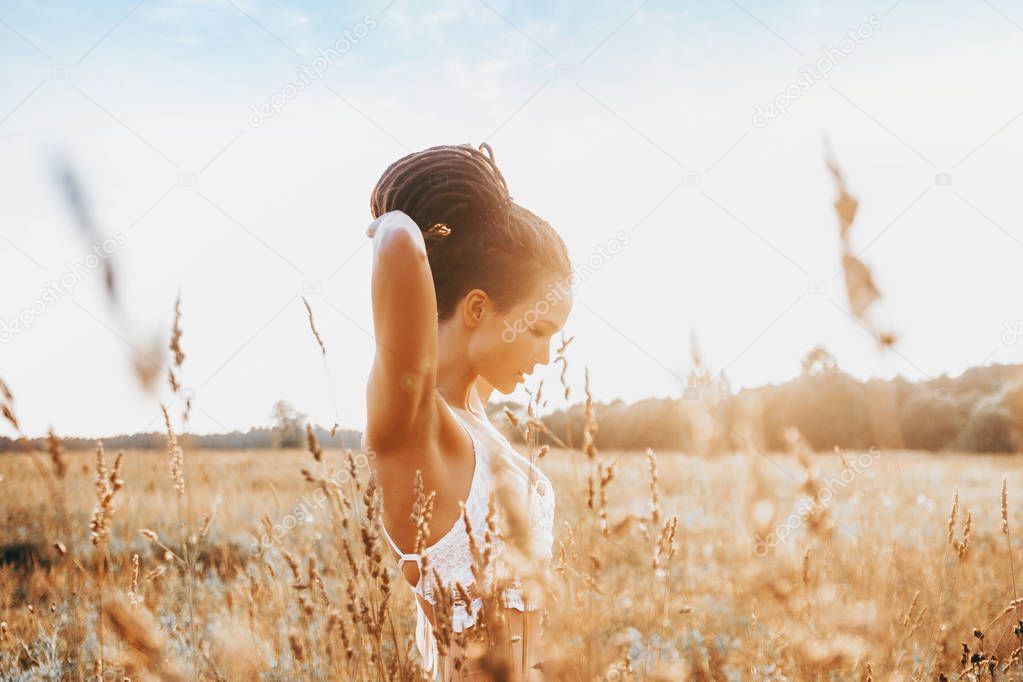 Young attractive girl in field at sunset. Outdoors romantic concept