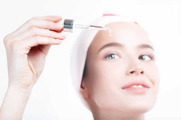 Mükemmel cilde sahip genç ve güzel bir kadın pipette yaşlanmaya duyarlı serum kullanıyor. Cilt bakımı ve yaş kozmetik konsepti