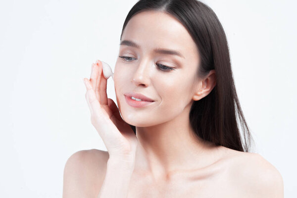 Young beautiful woman applies cream on clean perfect skin. Skin care and age cosmetics concept
