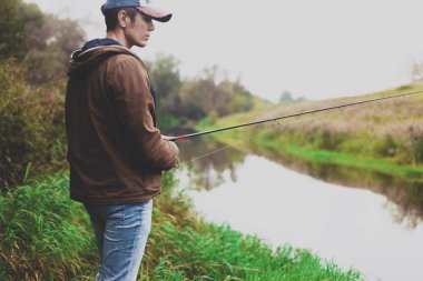 Genç balıkçı iplik ile Nehri'nde balık tutuyor. Hobi ve açık hava etkinlikleri kavramı