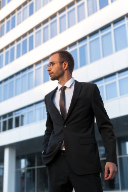 Resmi siyah elbiseli genç işadamı ofis binası önünde duruyor. İş portre