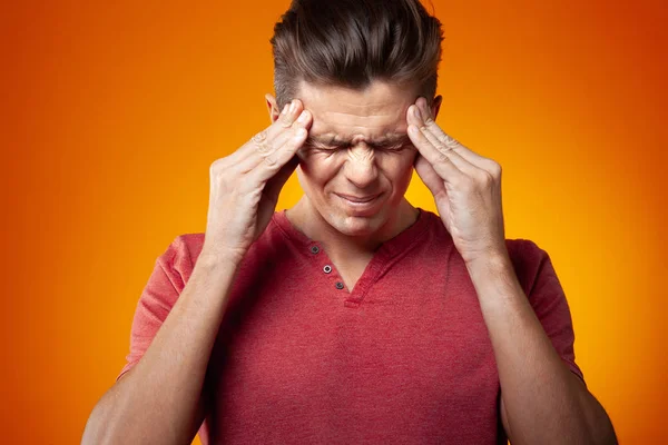 Adult Man Holding Fingers Temple Orange Background Stress Headache Concept — Stock Photo, Image