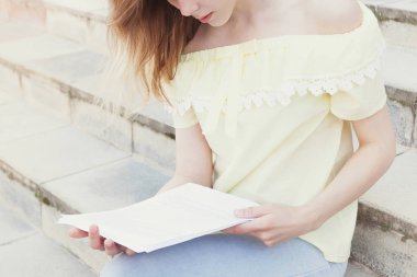 Genç güzel kız öğrenci merdivenlerde okuyor. Anonim yaşam tarzı portre