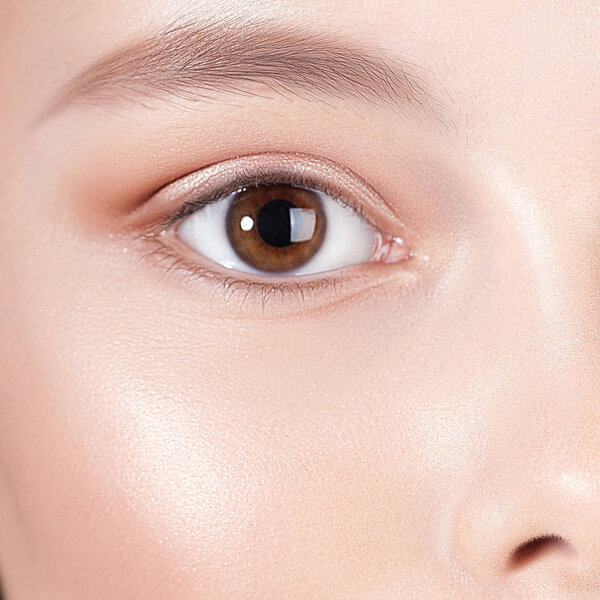 Глаз молодой улыбчивой девушки с чистой идеальной кожей крупным планом. Портрет красоты
