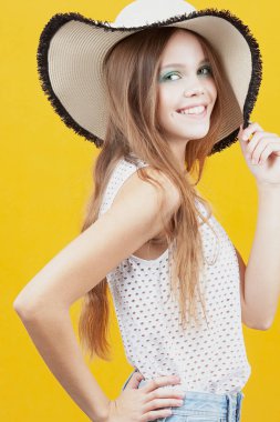 Hasır şapkalı genç kız sarı zemin üzerine gülümsüyor. Duygu ve hareketleri