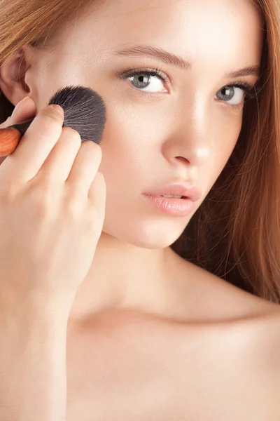 Young beautiful girl with brush for powder close-up. Cosmetics and care for young skin
