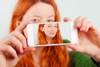 Kızıl saçlı kız telefonu kullanarak selfie yapma. Pozitif, yaşam tarzı, teknoloji ve sosyal ağ
