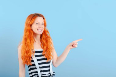 Kızıl saçlı kız gülümsüyor ve onun işaret parmağı ile puan. Promosyon ve ürünler gösterimi için şablon